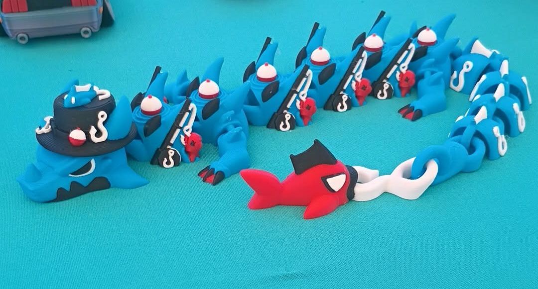 Blue articulated 3D-printed fishing dragon with tiny hat and rods
